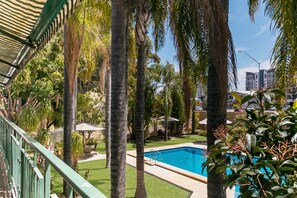 A swimming pool surrounded by palm trees and a covered patio area.