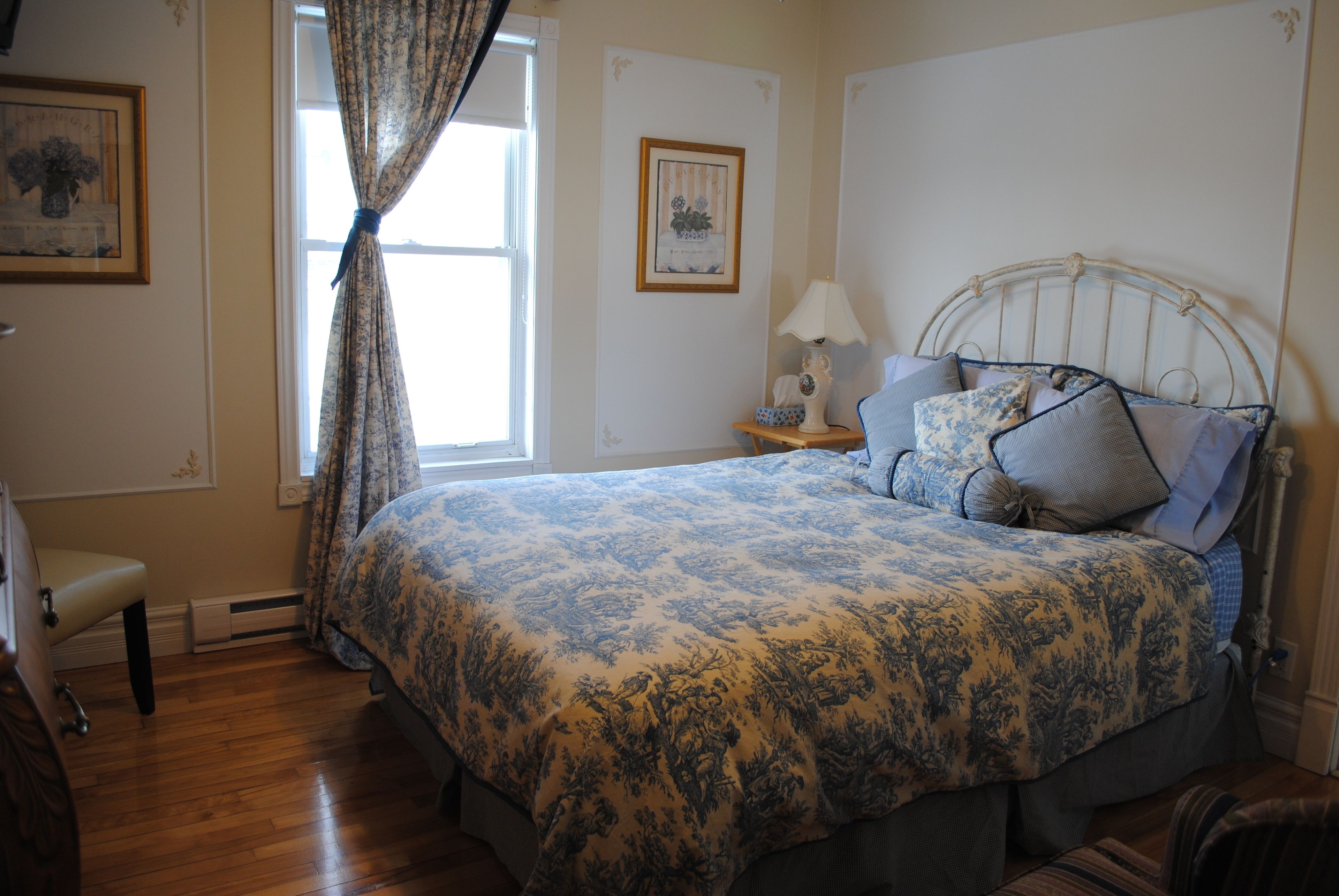 A bedroom with a bed, a nightstand, a lamp, and a chair.