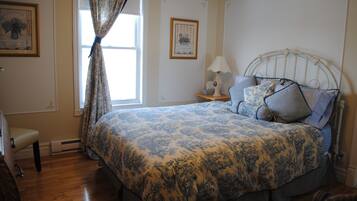 A bedroom with a bed, a nightstand, a lamp, and a chair.