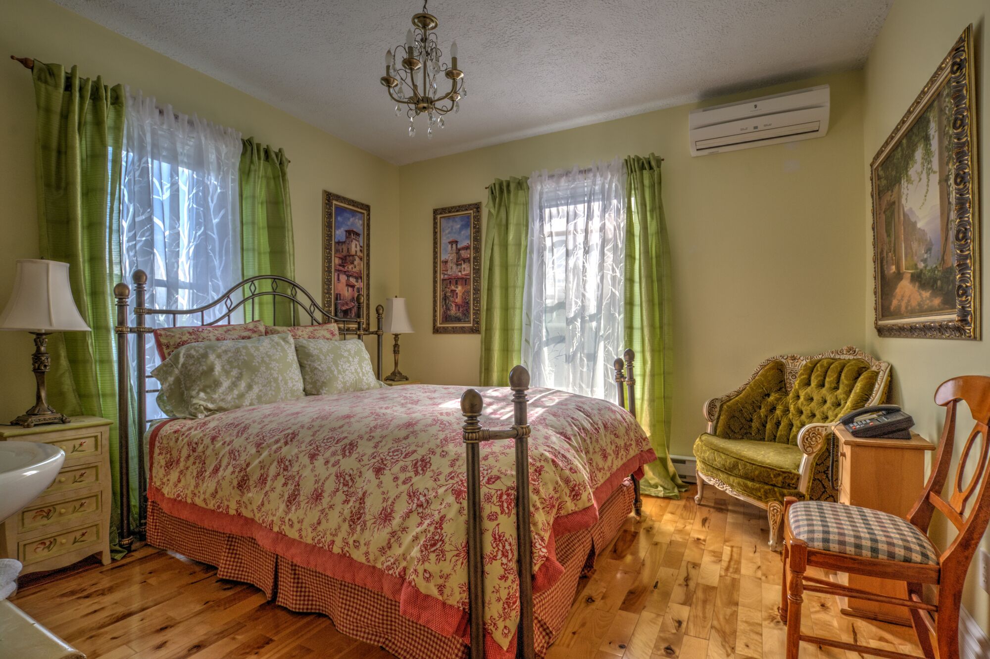 Un dormitorio con cama, una silla, cómoda, lámpara y un cuadro en la pared.