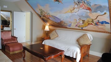 Une pièce avec une grande fresque murale, un canapé, un fauteuil et une table en bois.