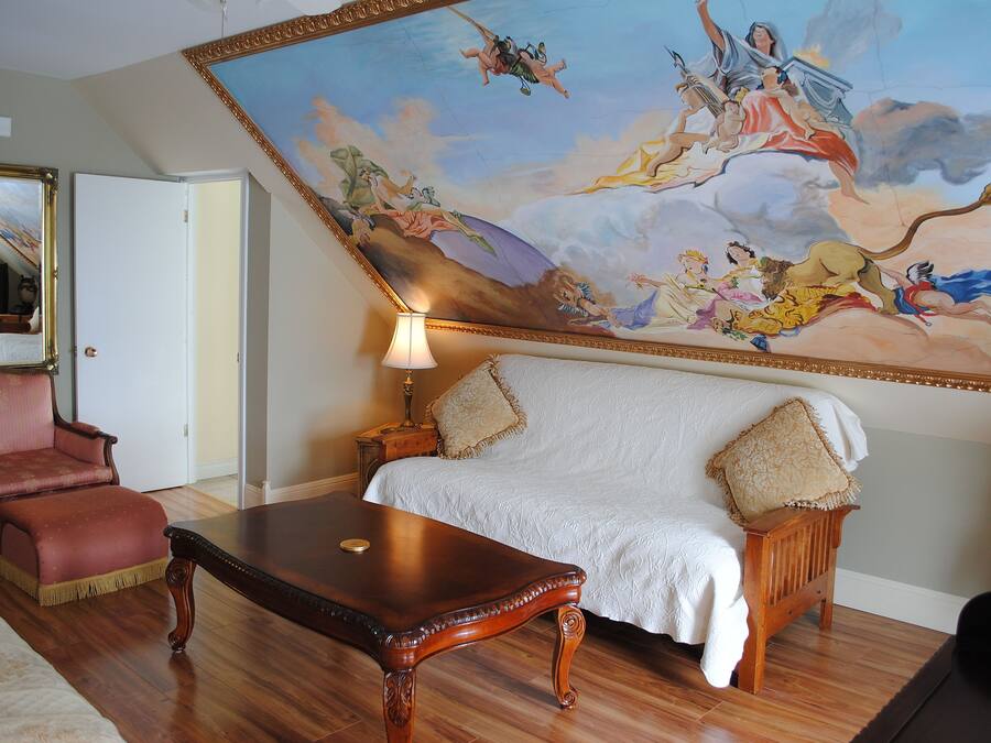 Une pièce avec une grande fresque murale, un canapé, un fauteuil et une table en bois.