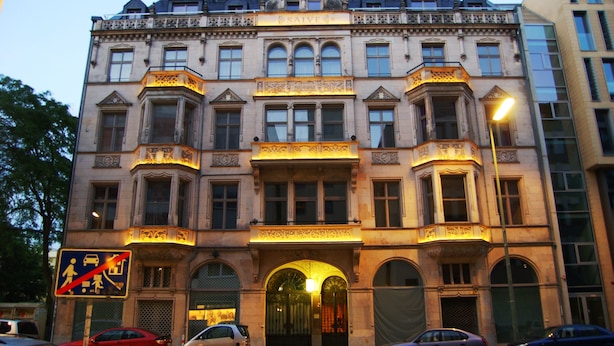 Ein historisches Gebäude mit aufwendiger Architektur, großen Fenstern und einem markanten Eingang.