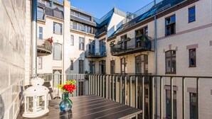 Ein Balkon mit Tisch, einer weißen Laterne und einem Blumenarrangement.