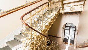 Eine imposante Treppe mit aufwendiger Metall- und Holzgeländerkonstruktion, die zu einer oberen Etage führt.