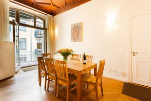 A dining area with a wooden table and chairs, a vase with flowers, and a painting on the wall. - Downtown City Landmark Near Checkpoint Charlie (Berlin)
