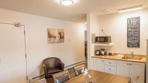 Une cuisine moderne avec des meubles blancs, un four à micro-ondes et un coin café.