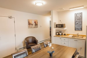 Une cuisine moderne avec des meubles blancs, un four à micro-ondes et un coin café.
