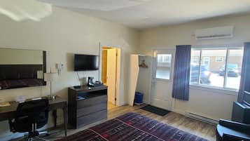 A hotel room with a bed, desk, chair, TV, wardrobe, and a window with curtains.