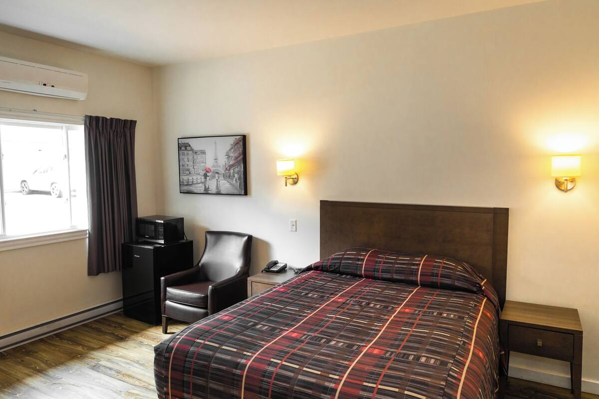 A hotel room with a bed, a desk, a chair, a television, and a picture on the wall.