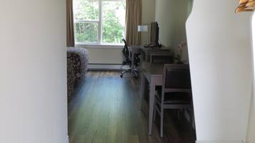 Una habitación con cama, escritorio, silla, televisor y ventana con cortinas.