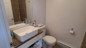 Un baño con lavamanos blanco, inodoro y espejo.