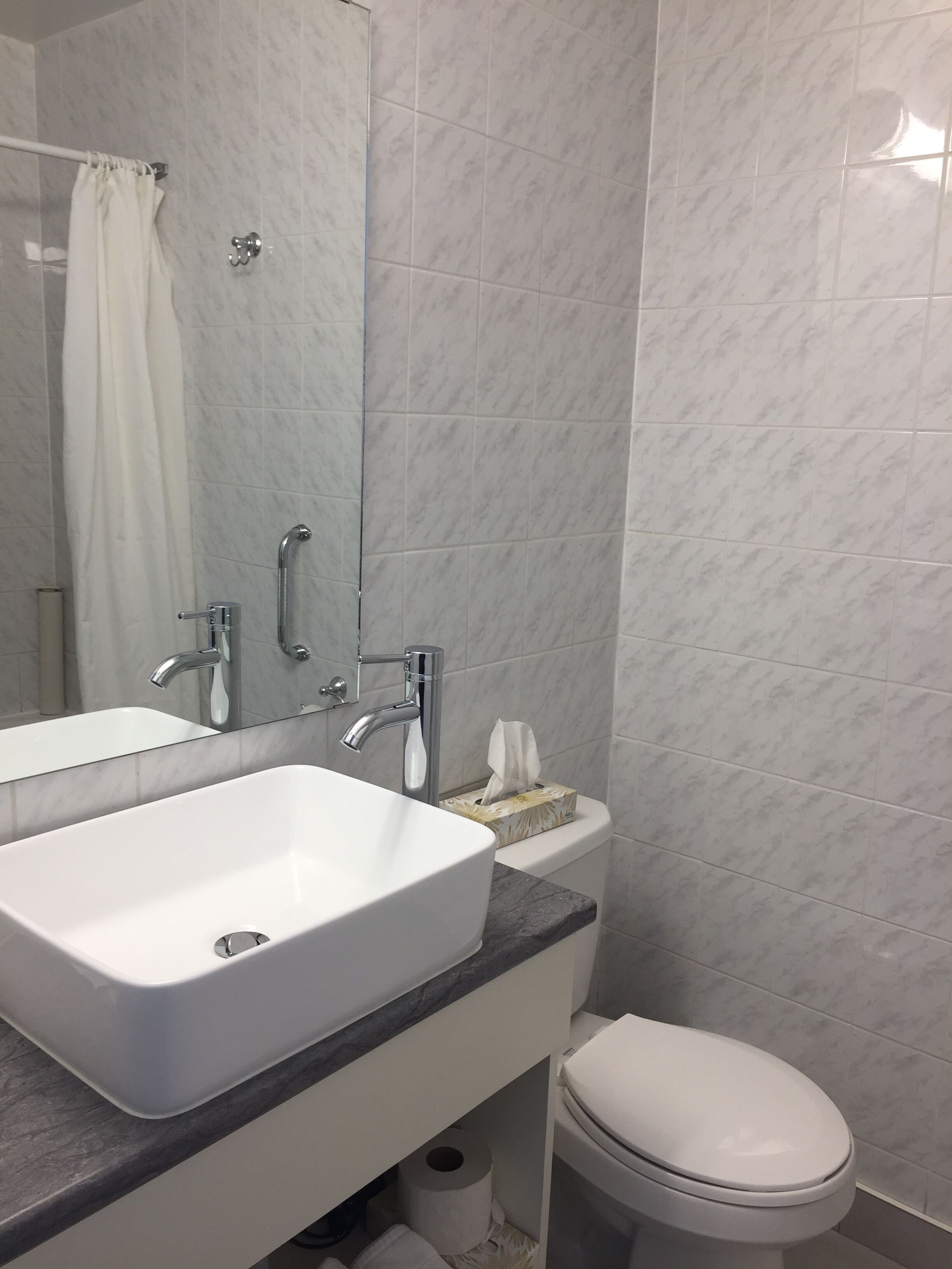 Baño con lavamanos, espejo y retrete blancos.