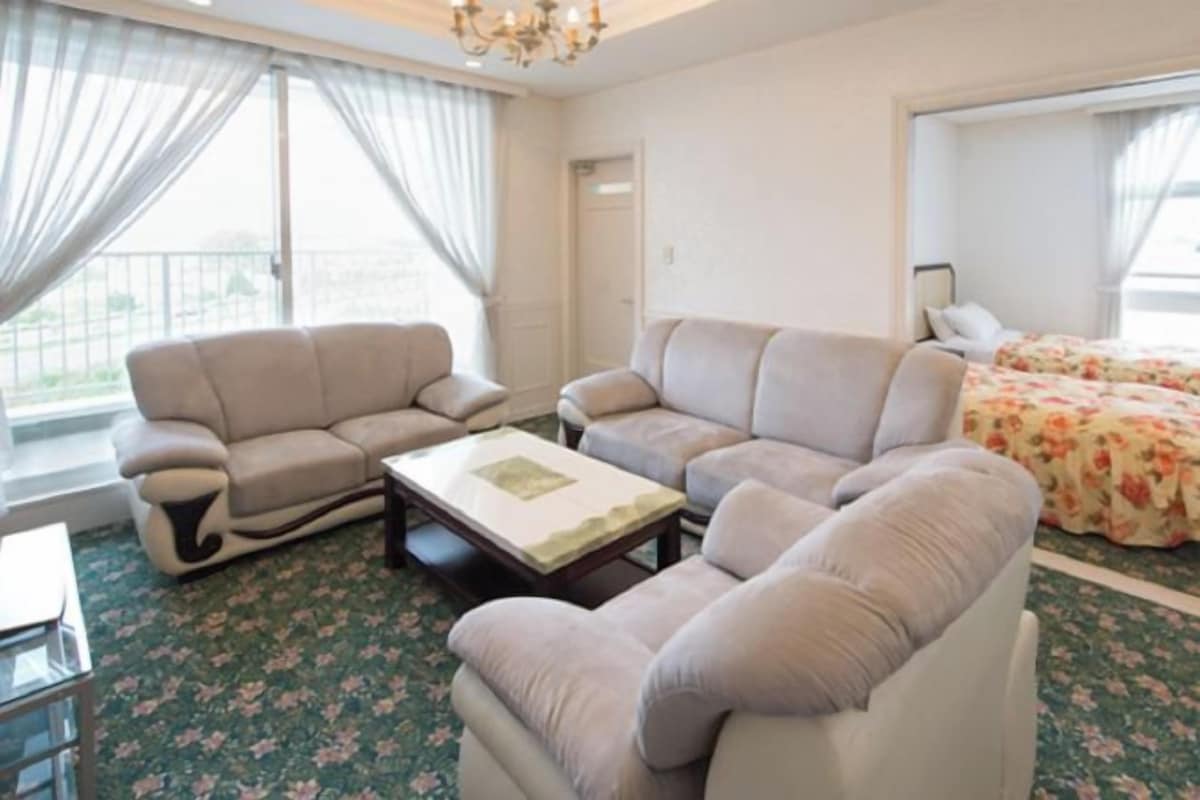 Una sala de estar con dos sofás, una mesa de centro y una cama con ropa de cama floral.
