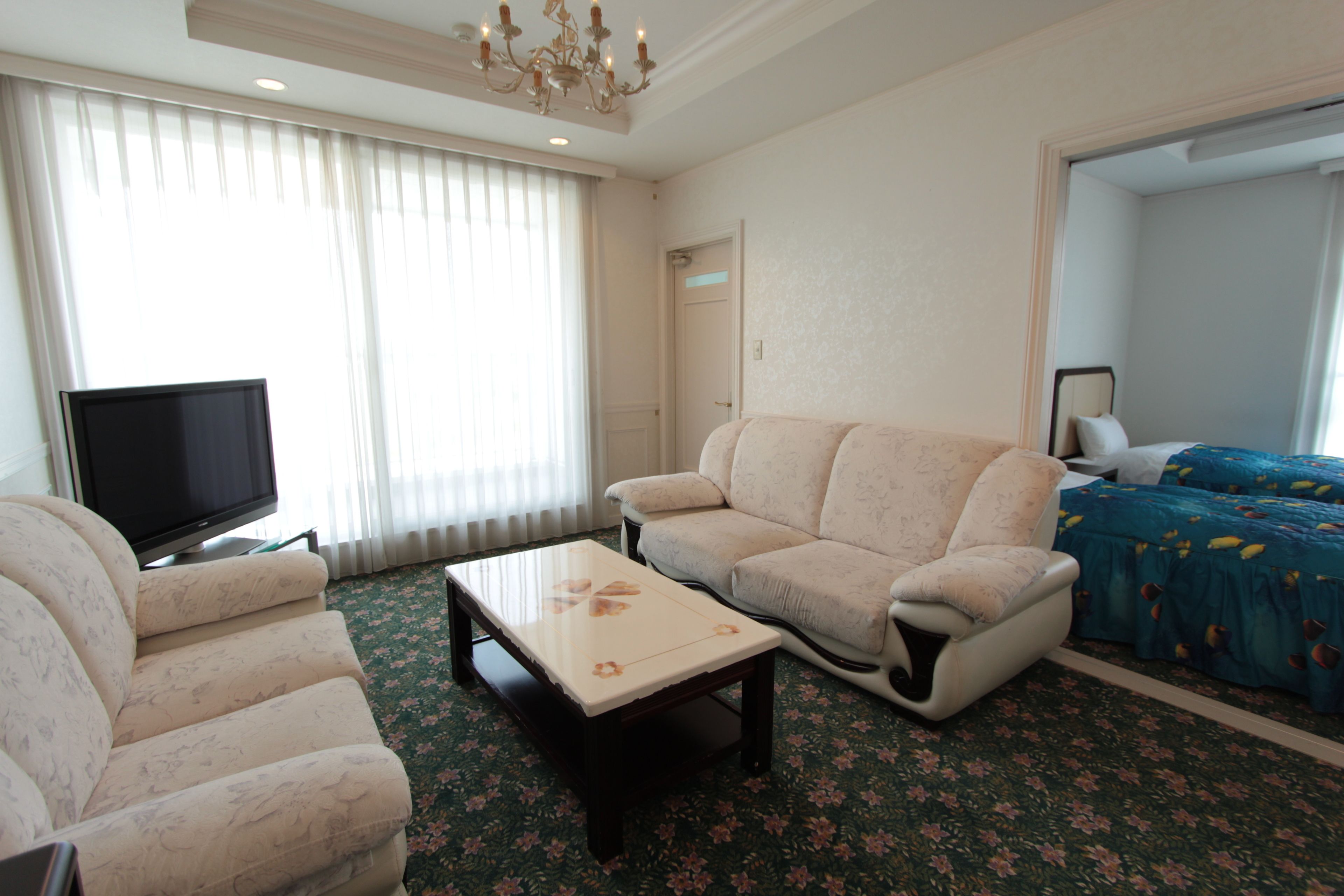 Een hotelkamer met een bank, een televisie, een bijzettafeltje en een bed met een bloemenprint.