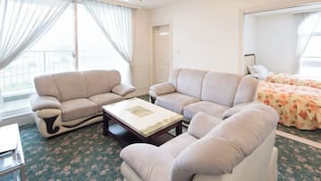 Un ampio soggiorno con un divano color beige, un tavolino da caffè e un letto con biancheria da letto a motivi floreali.
