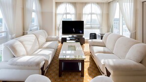 A modern living room with two white sofas, a large flat-screen TV, and a coffee table.