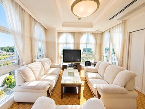 A spacious living room with a flat-screen TV, two sofas, a coffee table, and large windows with curtains. - SPA RESORT LiVEMAX (Mooka)