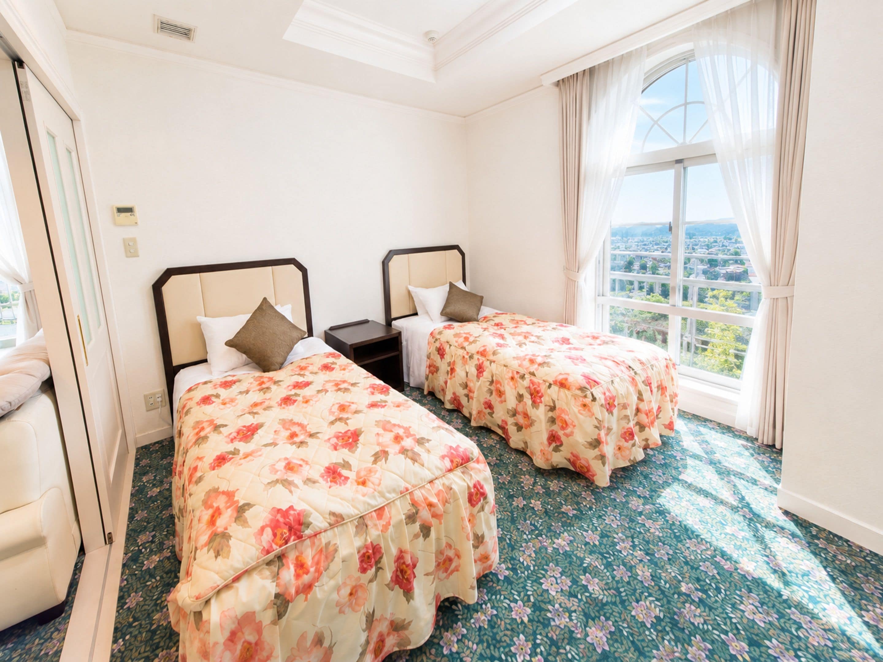 A hotel room with two beds, a window with a view, and a carpeted floor.