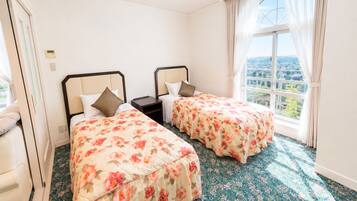 A hotel room with two beds, a window with a view, and a carpeted floor.