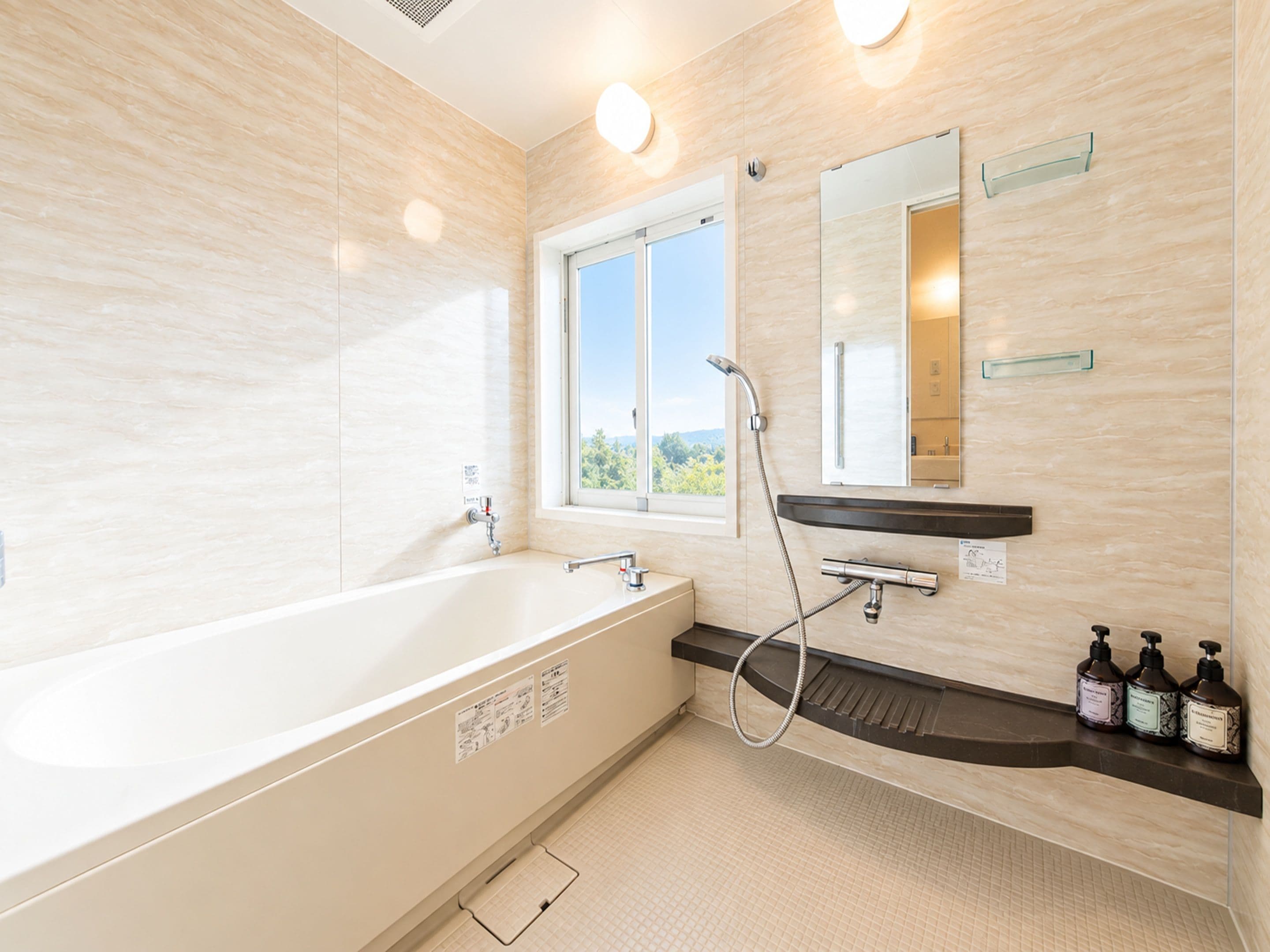 A modern bathroom with a freestanding bathtub, a window, and a vanity with soap dispensers.