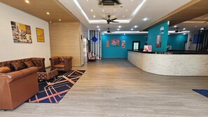 A lobby with a reception desk, leather sofas, a patterned rug, and ceiling fans. - iCheck inn Central Patong (Patong)
