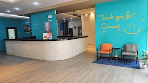 Un área de recepción con un mostrador curvo, un reloj y una pared con un cartel que dice 'Thank you for coming'.