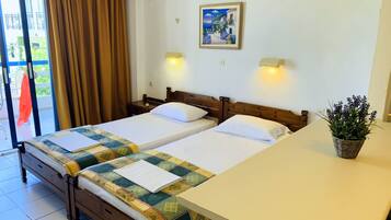 A hotel room with two beds, a balcony with curtains, a painting on the wall, and a potted plant on the table.