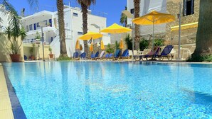 Une piscine d’un bleu éclatant, avec des chaises longues et des parasols jaunes.