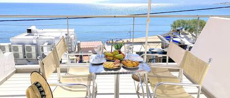 A balcony with a table set for two, overlooking a scenic view of the sea.