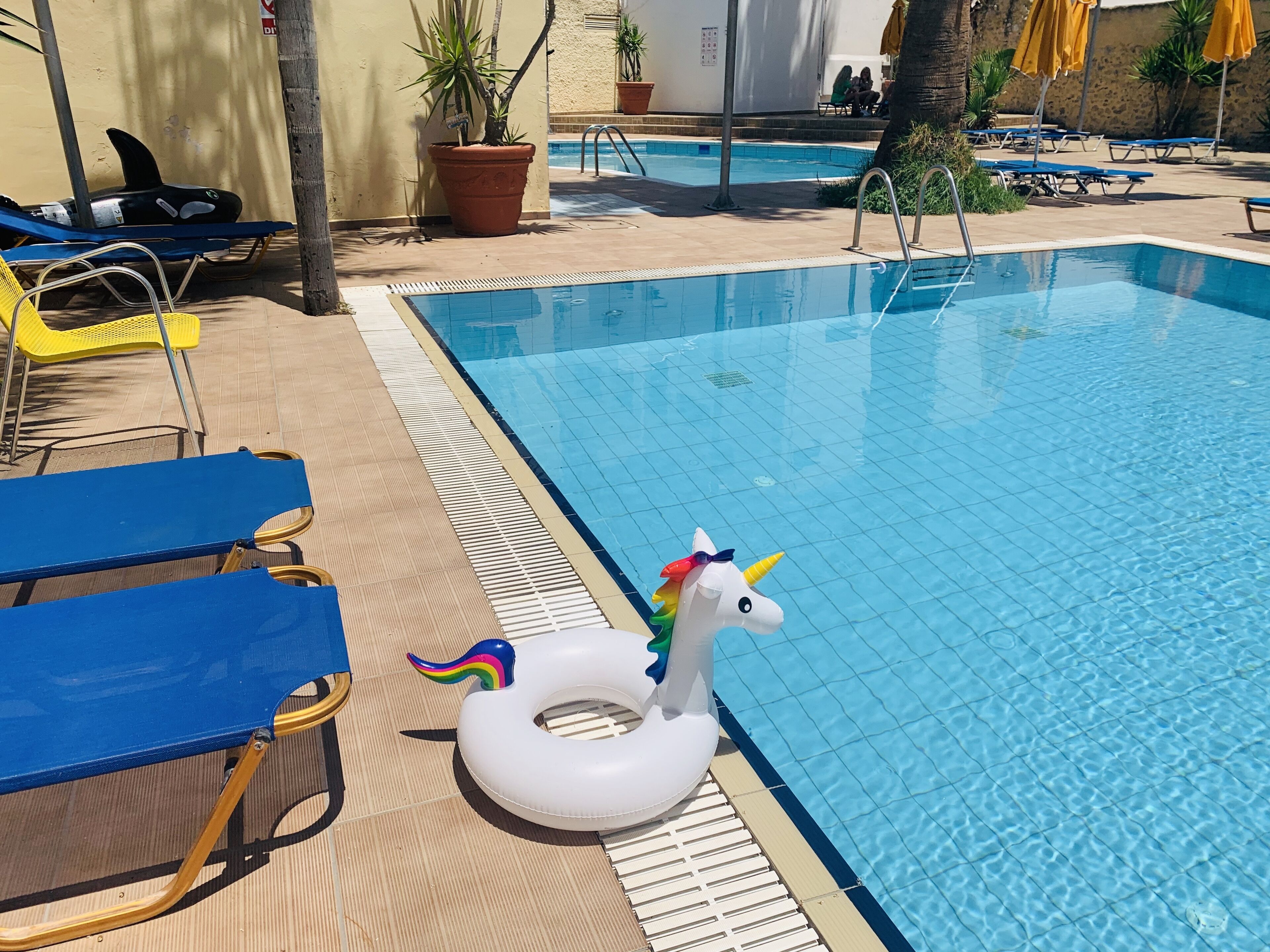 A swimming pool with blue water, surrounded by lounge chairs and a unicorn float.