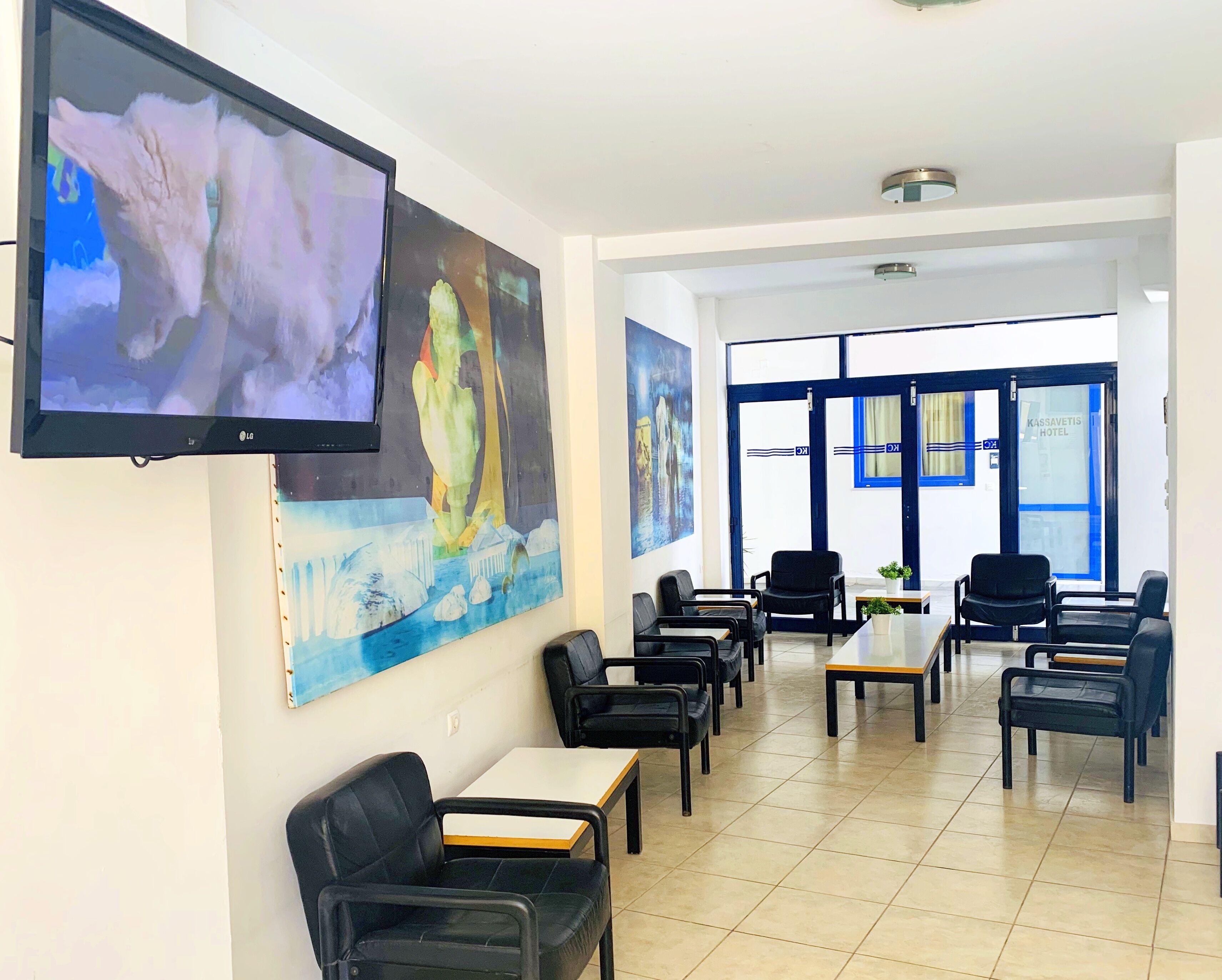A hotel lobby with a seating area, a large TV screen, and artwork on the walls.