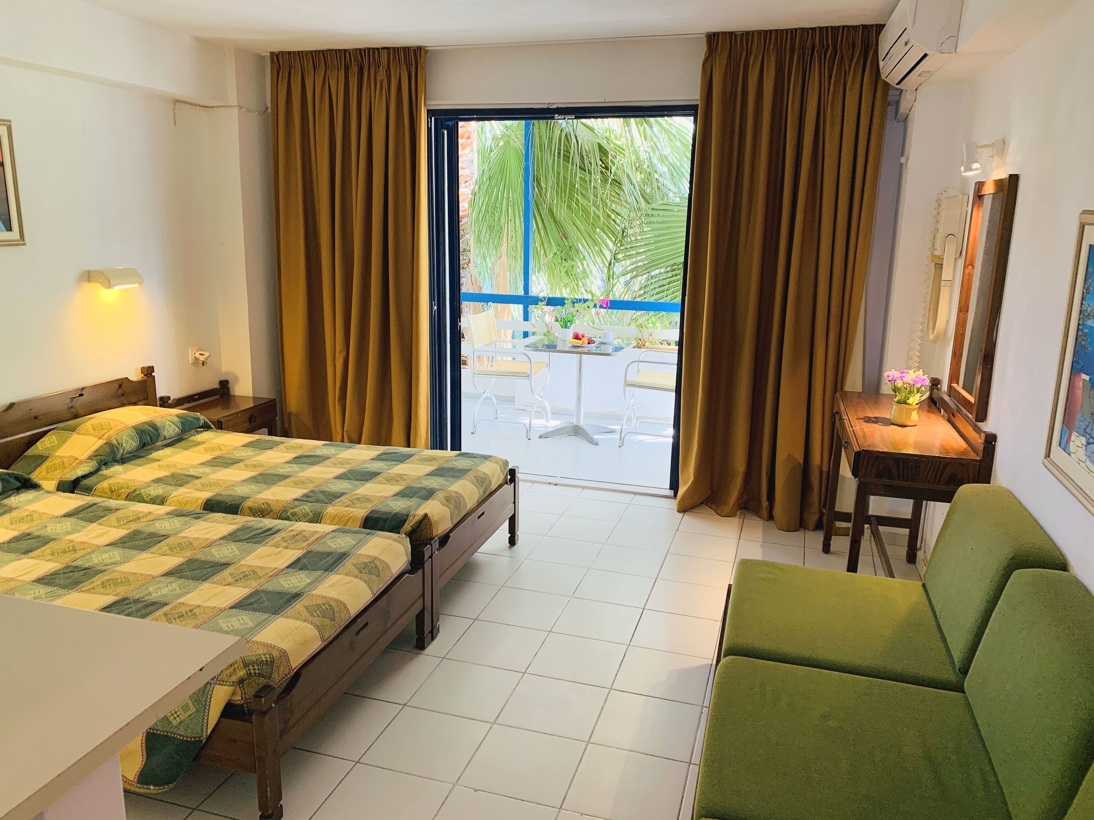 A hotel room with a bed, a desk, a chair, and a view of the outside.