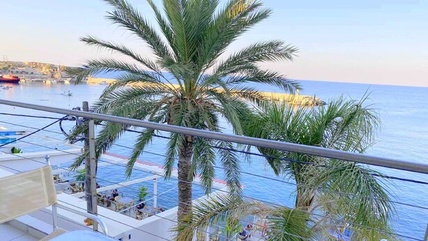 Un balcon avec vue sur la mer et les palmiers.