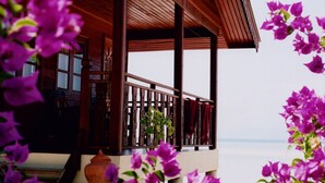 Un balcone in legno con ringhiera, vista su uno specchio d'acqua.