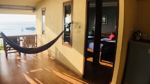 A room with a hammock, wooden flooring, a view of the sea, a bed, and a small kitchenette. - Suncliff Resort (Ko Pha-ngan)