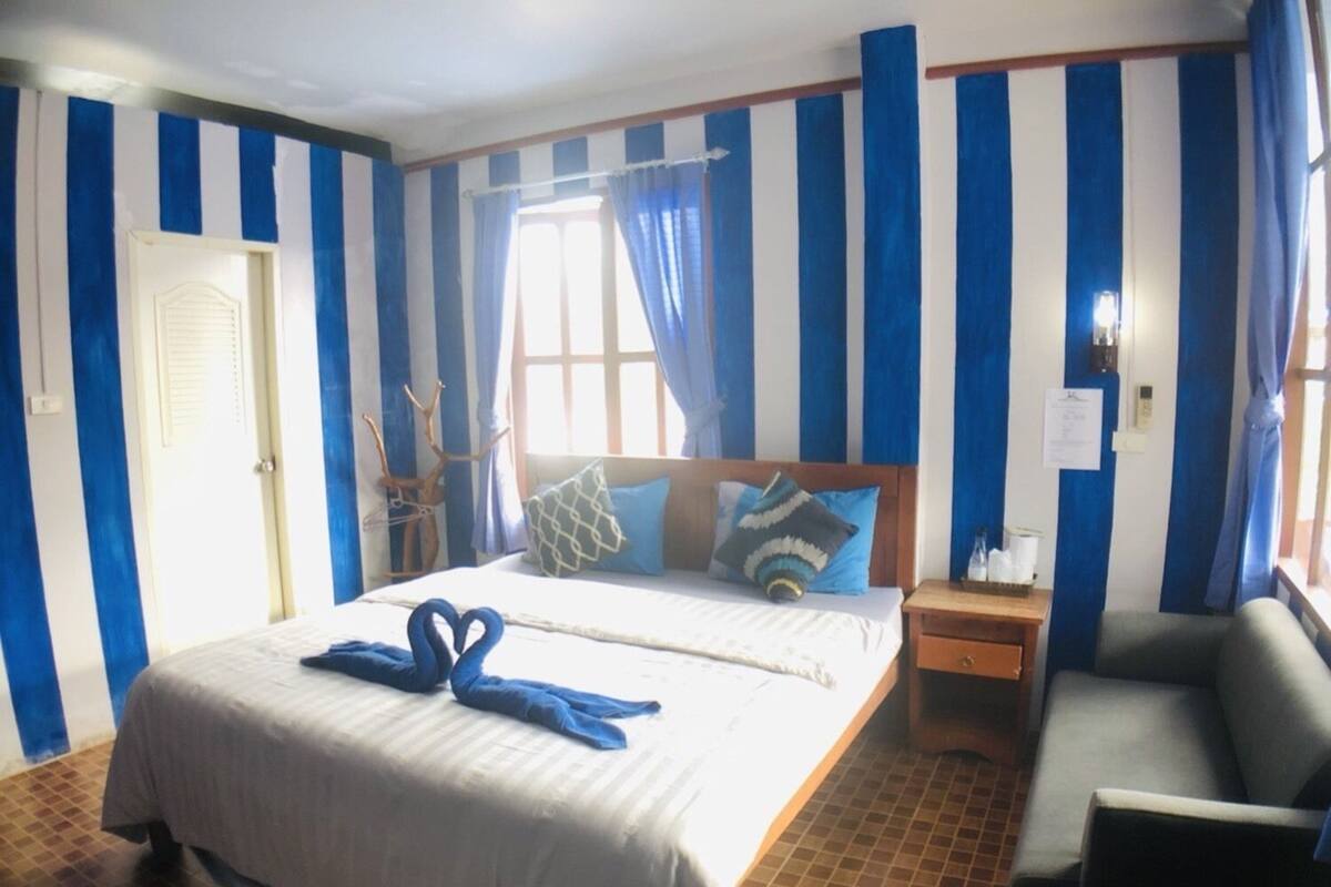 A hotel room with a bed, a nightstand, a chair, and a window with curtains.