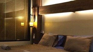 A hotel room with a bed, two pillows, a headboard, and a window with blinds. - Suncliff Resort (Ko Pha-ngan)