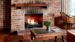 A cozy living room with a brick fireplace, a flat-screen TV mounted above it, and comfortable seating. - The Terrace at The Settlement (Cranbourne)