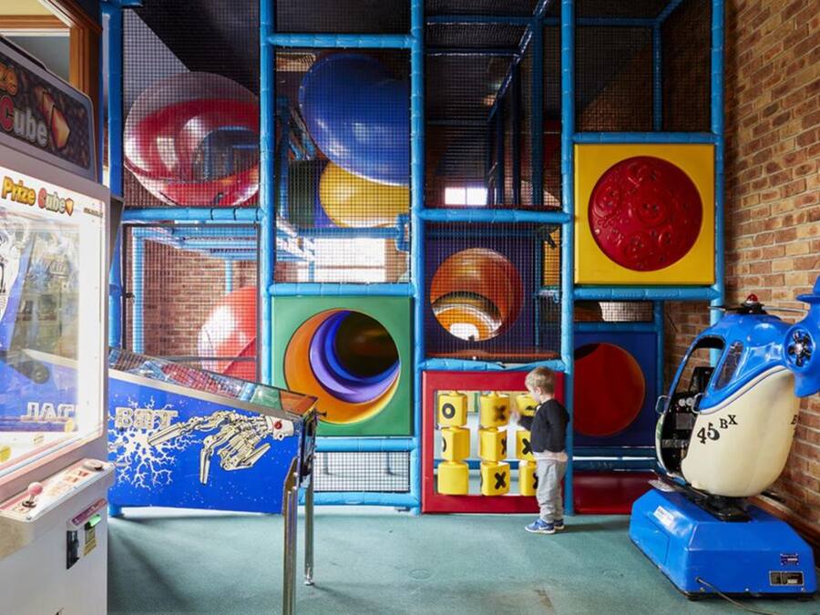 A play area with a climbing wall, a blue and yellow obstacle course, and a claw machine.