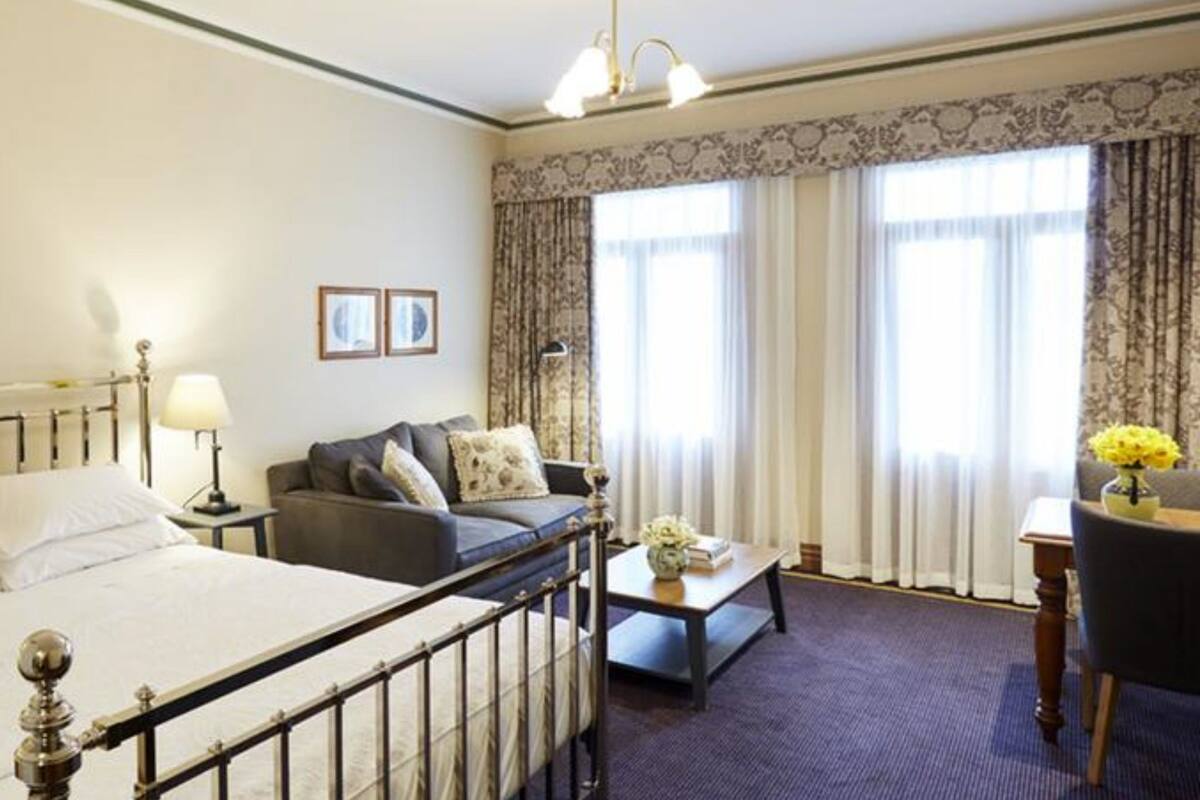 A hotel room with a bed, a sofa, a desk, and a chair.