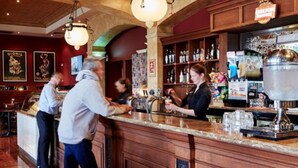 A bar area with wooden counters, hanging lights, and a variety of bottles and glasses. - The Terrace at The Settlement (Cranbourne)