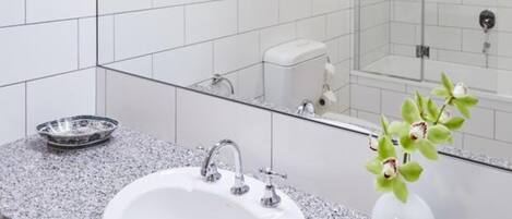 A modern bathroom with a white sink, granite countertop, and a mirror.