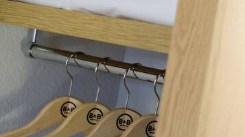 Una habitación de hotel con una cama bien hecha, una toalla y perchas de madera con el logotipo del hotel.