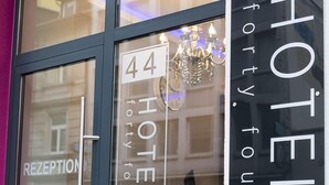 A hotel entrance with a reception area, a chandelier, and the name 'HOTEL forty four' on the glass doors. - Hotel Forty Four (Frankfurt)