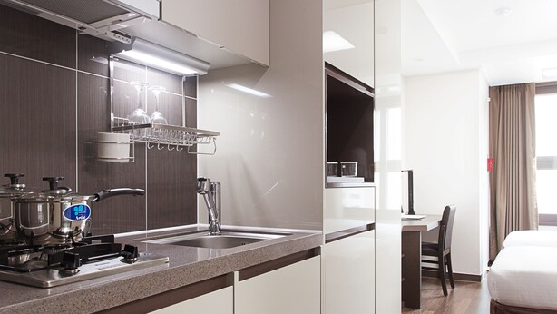 A modern hotel room with a kitchenette, a bed, and a desk area.