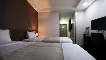 Ett hotellrum med två sängar, ett skrivbord, en stol, en TV och en spegel.