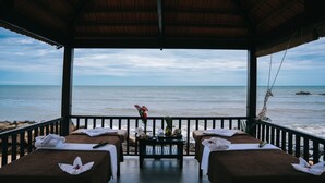 A beachside spa with two massage tables, a small table with amenities, and a view of the ocean. - Sea Sense Resort (Phu Quoc)