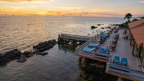 An outdoor terrace with blue lounge chairs and tables, overlooking a calm sea at sunset. - Sea Sense Resort (Phu Quoc)