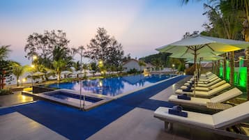 Een buitenzwembad, parasols bij het zwembad en ligstoelen